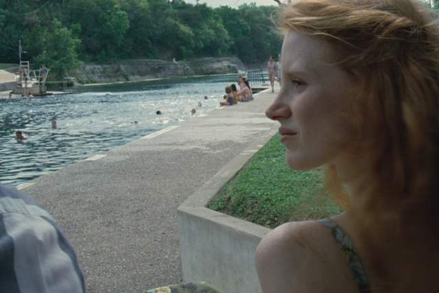 Tree of Life Screengrab, showing Jessica Chastain looking to the side of the frame. Behind her, people are swimming in Barton Springs Pool