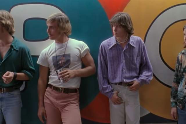 Screengrab from Dazed and Confused showing actors Sasha Jensen, Matthew McConaughey, Jason London and Wiley Wiggins standing up against the wall at the Emporium