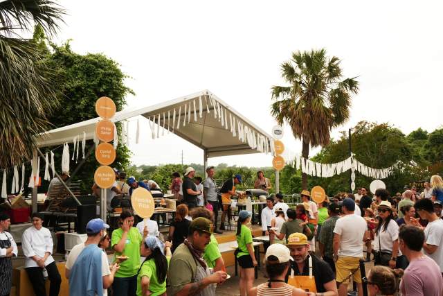 A group of men and women standing in front of an outdoor food tent at Field Guide Festival.