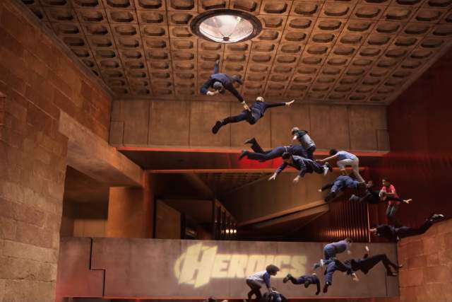 We Can Be Heroes screengrab with kids floating towards the ceiling inside the Heroes Headquarters Interior. The word Heroes is visible on the wall
