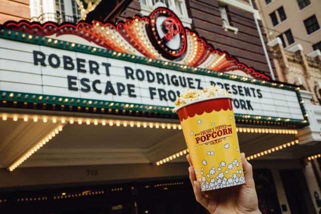 Image of the marquee at the Paramount Theater with a hand holding up a cup of popcorn in front of it.
