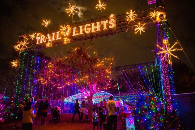 Image from a low perspective of the large illuminated sign stating "Trail of Lights" at the entrance to the event.