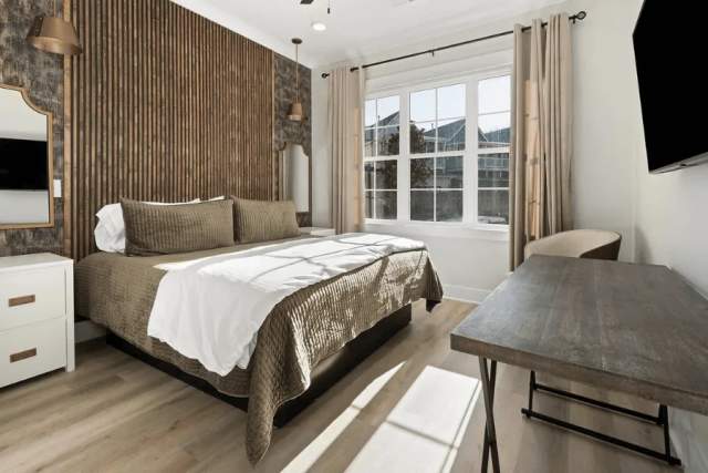 A bedroom in the new Buck Creek BnB includes stylish furniture and a cozy bed. The window is open, letting in sunlight from the outdoors.