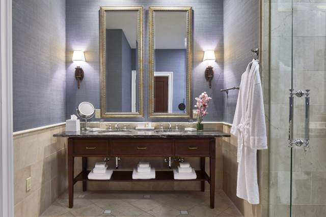 Hotel bathroom with double mirror over sink and robe hanging on the wall next to shower door