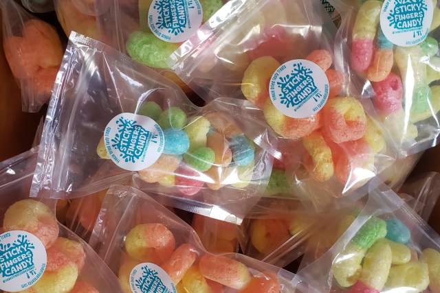 Clear baggies full of colorful candies sit in a pile. Label reads "Freeze dried tasty treats, Sticky Fingers Candy"