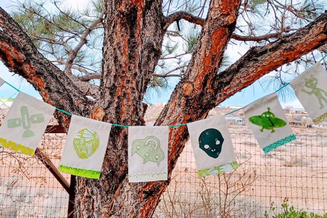 flags hang across a tree depicting different alien related charcters in green