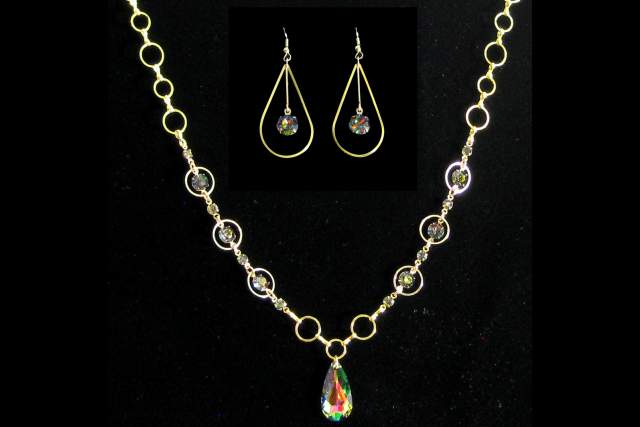 Gold necklace with multicolored gemstones displayed against a black background, accompanied by matching earrings.