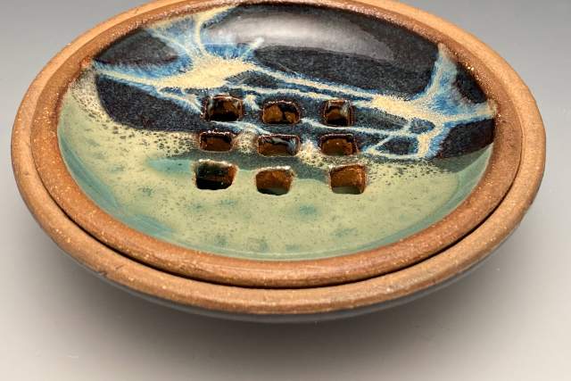 Decorative ceramic bowl featuring a glossy, multicolored glaze with a distinctive pattern and sunken square details in the center.