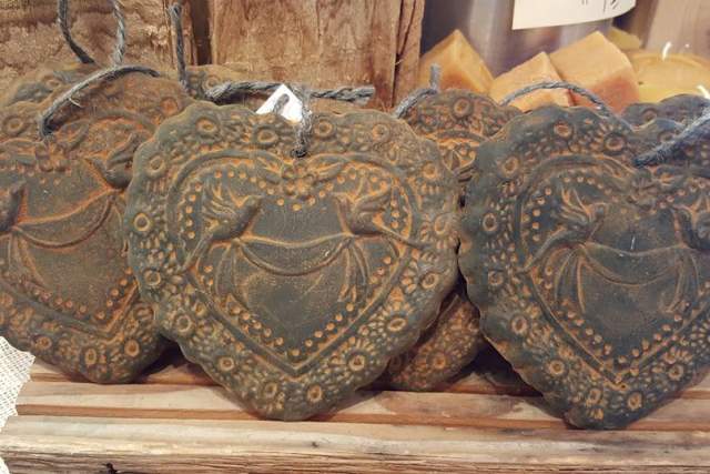 A row of ornately carved heart-shaped beeswax ornaments displayed on a shelf.