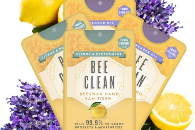 Image of three 'Bee Clean' beeswax hand sanitizer packets featuring citrus and peppermint scents, decorated with fresh lemons and purple lavender flowers.