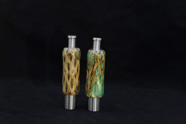 Two decorative bottles with artistic wood bodies and stainless-steel tops, displayed against a black background.