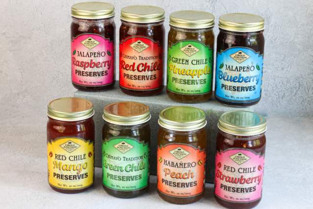Eight jars of various preserves with vibrant labels featuring different flavors.