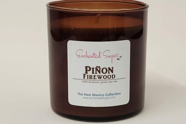 A brown glass candle jar labeled "Enchanted Sugar Piñon Firewood" from the New Mexico Collection.