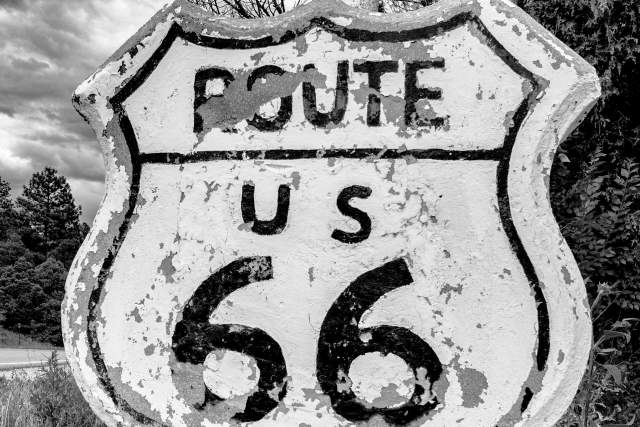 Black and white image of a weathered sign that reads "Route US 66"