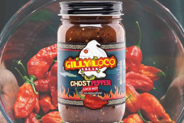 A jar of Gilly Loco Ghost Pepper Salsa surrounded by ghost peppers.