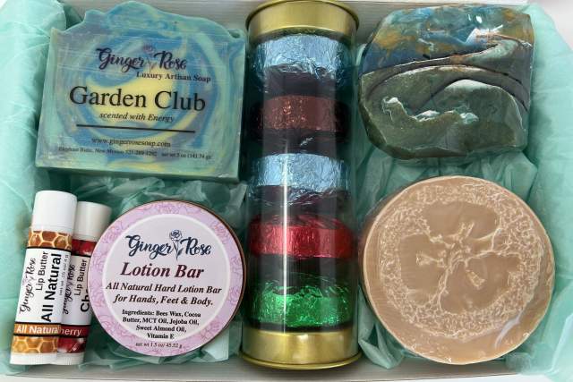 A selection of Ginger Rose selfcare products including soaps, lotion bars, and ribbons in a gift box.