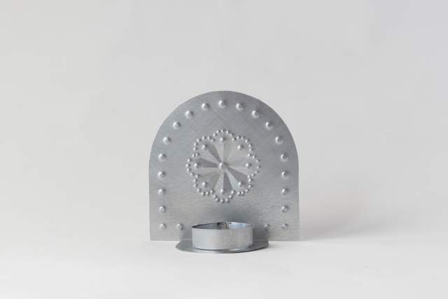 A metal candle holder with a decorative perforated design featuring a central star pattern and circular accents, set against a plain white background.