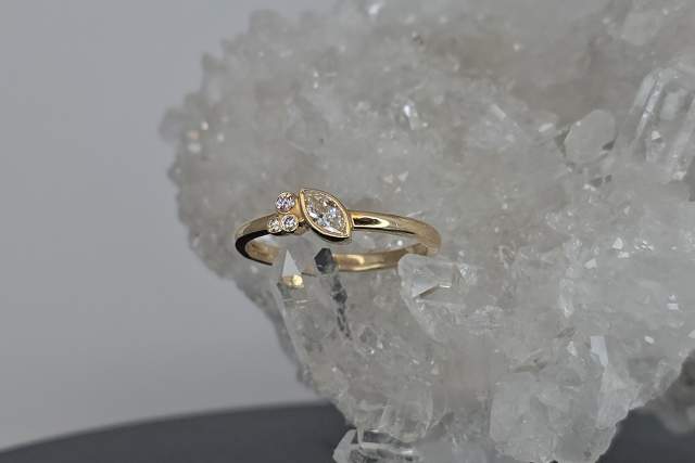 A gold ring with multiple diamonds is positioned against a background of rough, transparent crystals.