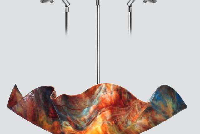 A vibrant, multicolored modern chandelier with an artfully wavy glass design hangs from a metallic fixture.