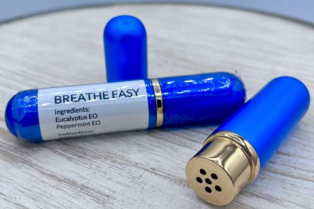 Two blue Breathe Easy inhalers with gold caps, displaying ingredients on the label, placed on a white surface.