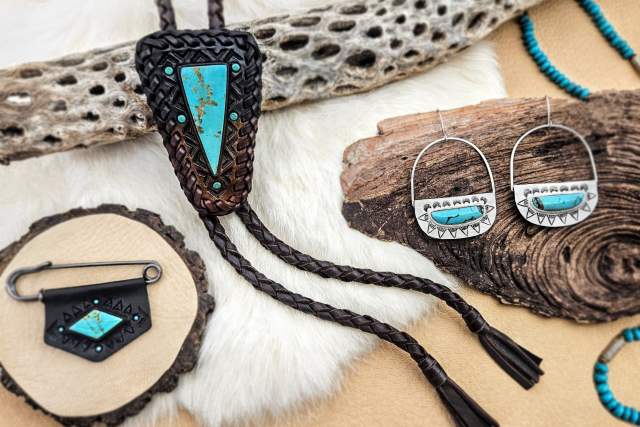 Turquoise and silver jewelry displayed on natural materials, including a wood piece and textured fabrics. Featured items include a bolo tie, earrings, and a keychain.