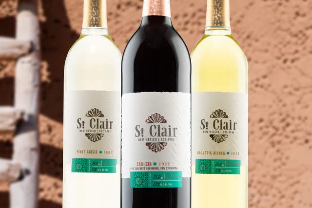 Three bottles of St Clair wine, with two white and one red, displayed against a textured beige background.