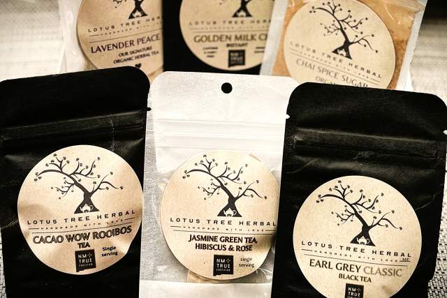 Assortment of Lotus Tree Herbal tea bags including flavors like Lavender Peace, Golden Milk, Chai Spice, Cacao Wow Rooibos, Jasmine Green Tea, Hibiscus & Rose, and Earl Grey Classic.