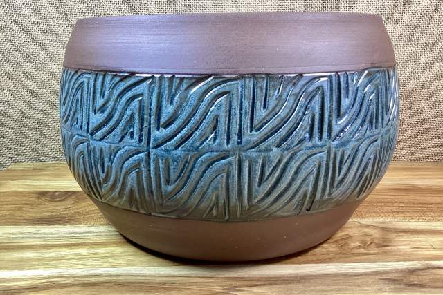 Decorative bowl with an embossed pattern sitting on a wooden surface.