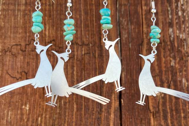 Four earrings featuring silver bird silhouettes and turquoise beads displayed on a wooden background.