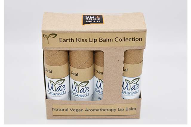 A cardboard box labeled "Ma’s Botanicals" containing three tubes of lip balm is displayed. The packaging highlights "Earth Kiss Lip Balm Collection" and "Natural Vegan Aromatherapy Lip Balm."