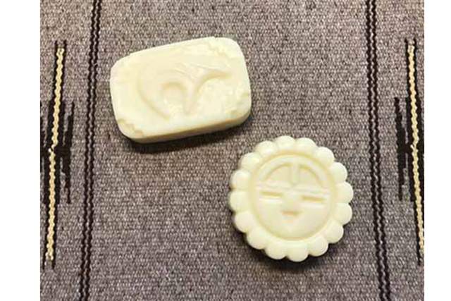 Two bars of soap with intricate designs, placed on a striped fabric surface.