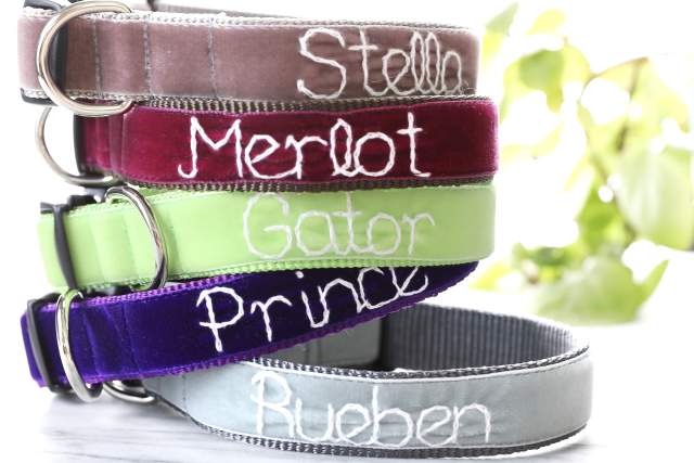 A stack of colorful personalized pet collars with different names embroidered on them, including Stella, Merlot, Gator, Prince, and Ruben, displayed in front of a blurred background.