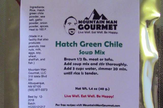 A vacuum-sealed package of Mountain House Freeze Dried Hatch Green Chili, displayed on a reflective surface.