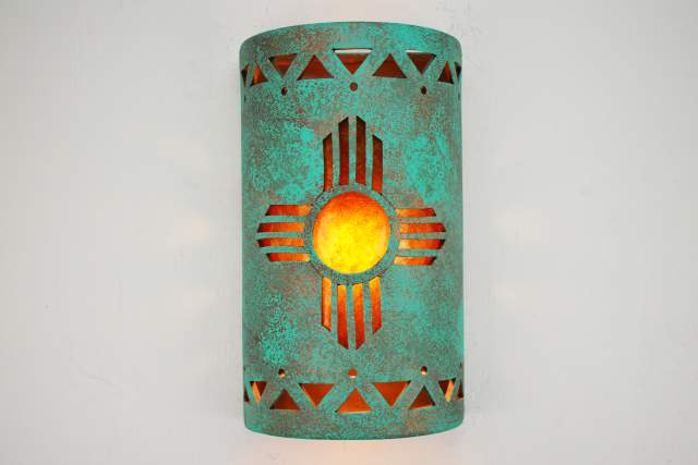 A turquoise copper wall sconce with an orange zia cutout