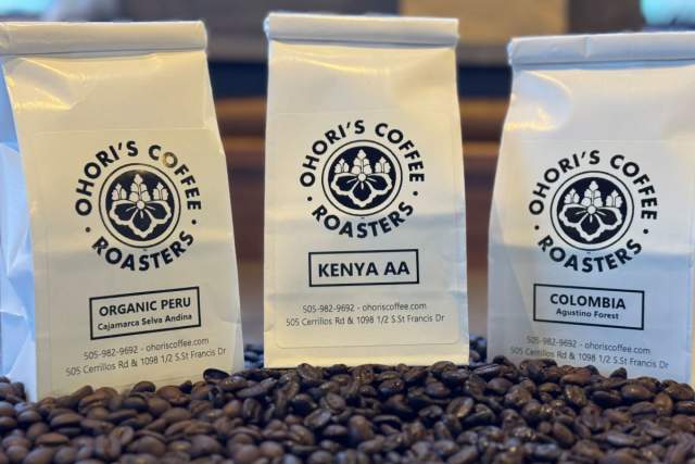 Three bags of Ohori's Coffee Roasters coffee, labeled Organic Peru, Kenya AA, and Colombia, displayed behind a spread of coffee beans.