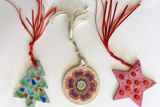 Three handmade Christmas ornaments displayed on a white background: a green mosaic tree, a circular ornament with a colorful floral pattern, and a red star with polka dots.