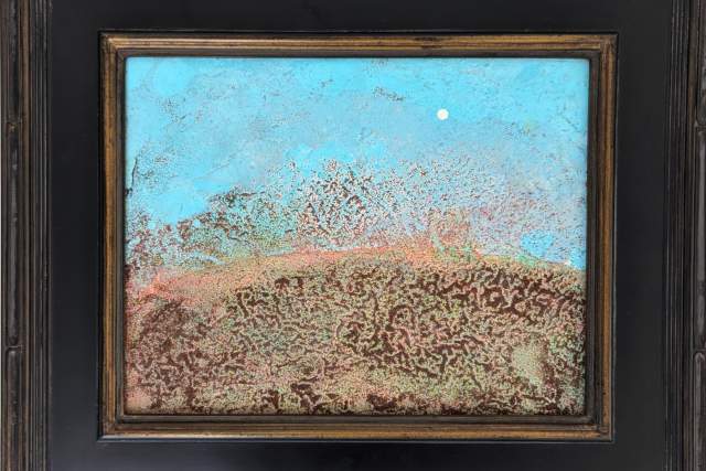 Artwork depicting a colorful abstract landscape with red and brown earthy textures in the foreground, blending into a blue and turquoise sky, displayed in a decorative black frame.
