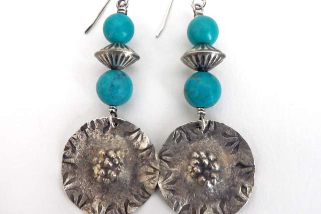 A pair of earrings featuring turquoise beads and silver floral medallions.