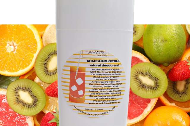 A bottle of Tayori natural deodorant with a sparkling citrus scent, displayed in front of a vibrant background of assorted citrus fruits like oranges, lemons, limes, and kiwis.