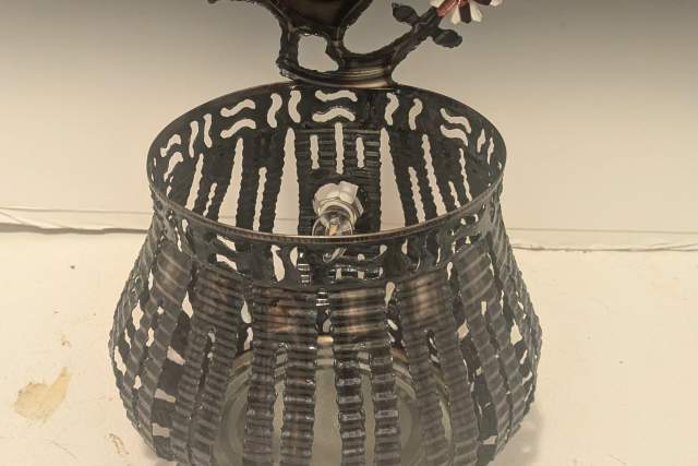 Decorative black and white cage with a stylized quail on top, featuring floral patterns on its body and tail.
