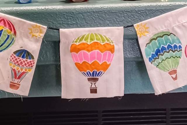 Decorative banner displaying various colorful hot air balloon designs hung above a fireplace.
