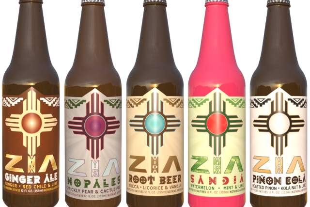 Five bottles of Zia Beverages in various flavors, each featuring a distinct colorful label with Native American-inspired designs. From left to right: Ginger Ale, Red Chile Ale, Root Beer, Licorice & Watermelon Ale, and Piñon Cola.