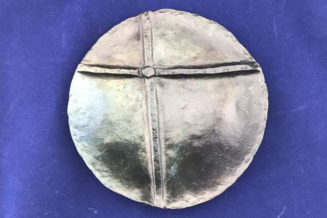 a hammered steel bowl depicting the New Mexico Zia symbol sits on a blue background