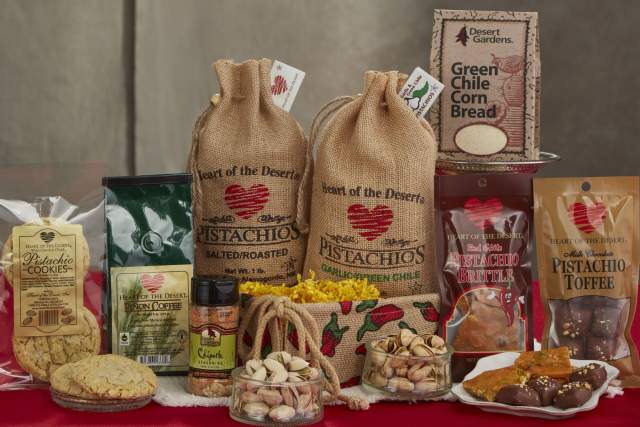 A variety of products in different packaging sit on a red table. The labels read "Heart of the Desert Pistachios"