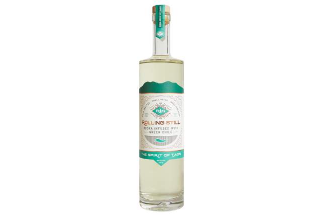 A clear bottle of Vodka with a white and turquoise label. The label reads: Hand Crafted, Small Batch, Water from 9200 (elevation). Rolling Still, Vodka Infused with Green Chile, The Spirit of Taos