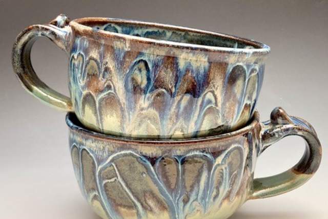 Two teacups with various earthen colors sit stacked inside one another