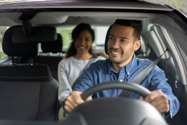 Latin American driver transporting a woman in a car while talking to her