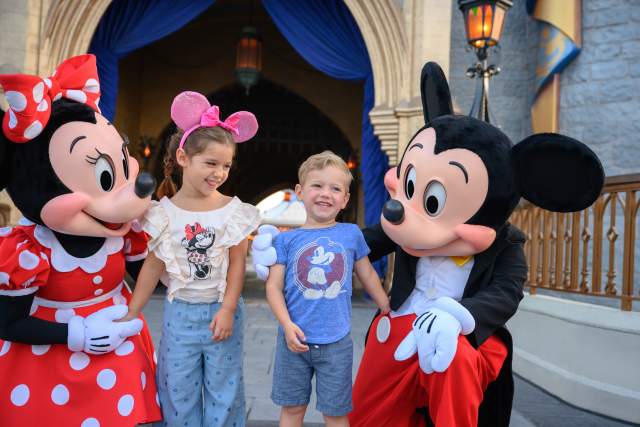 Mickey and Minnie Mouse with two children at Disney World