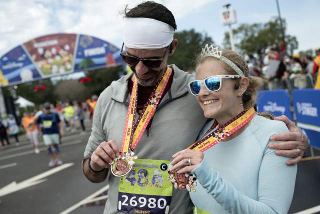 (Jan. 7, 2024) Charlotte area runner Susan Moriceau, who is blind, celebrates with her husband after completing the Walt Disney World Marathon on Sunday. The pair, who run tethered together, also ran the 5K, 10K and weather-shortened half marathon earlier in the weekend to complete the “Dopey Challenge’’ at Walt Disney World Resort in Lake Buena Vista, Fla. (Mark Ashman, photographer)