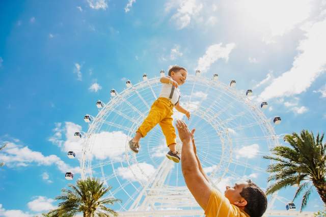 father throwing son up in air in front of The Wheel at ICON Park